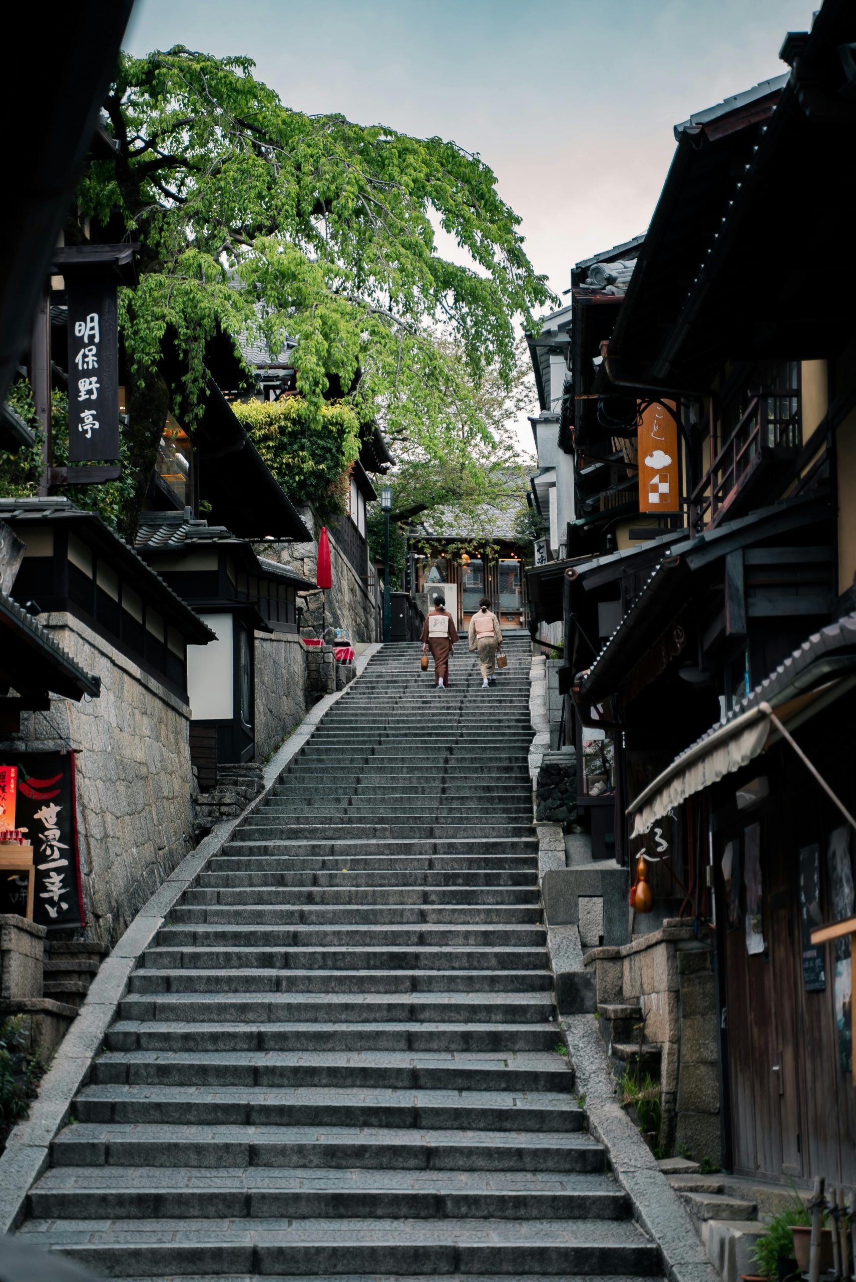 Explorez une charmante rue étroite de Kyoto avec des maisons en bois traditionnelles et des escaliers.