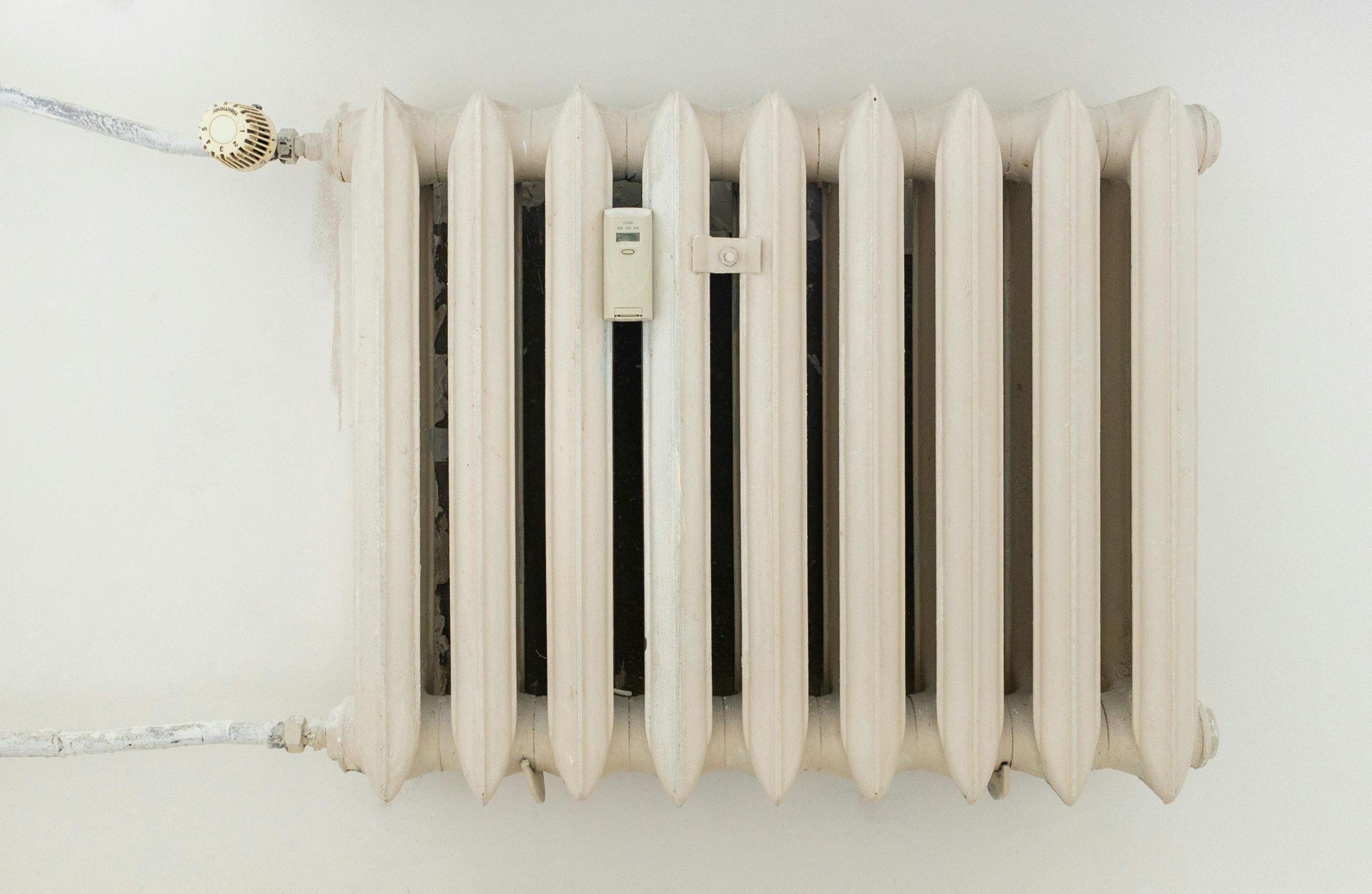 Un radiateur métallique blanc classique sur un mur uni, illustrant un design d'intérieur minimaliste.