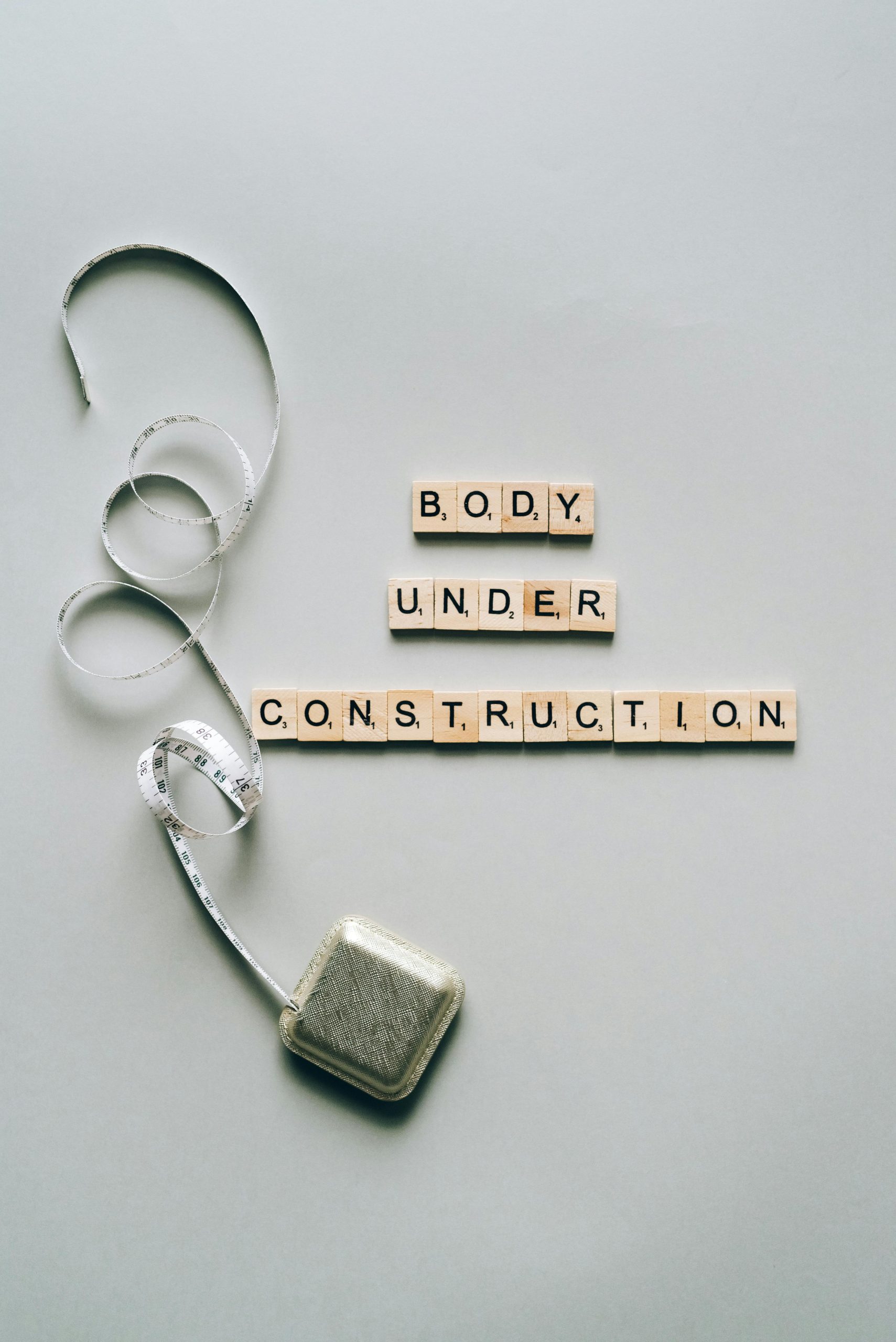 Inspiring fitness concept with 'Body Under Construction' in Scrabble tiles and a tape measure. Concept de remise en forme inspirant avec 'Body Under Construction' en tuiles de Scrabble et un mètre ruban.