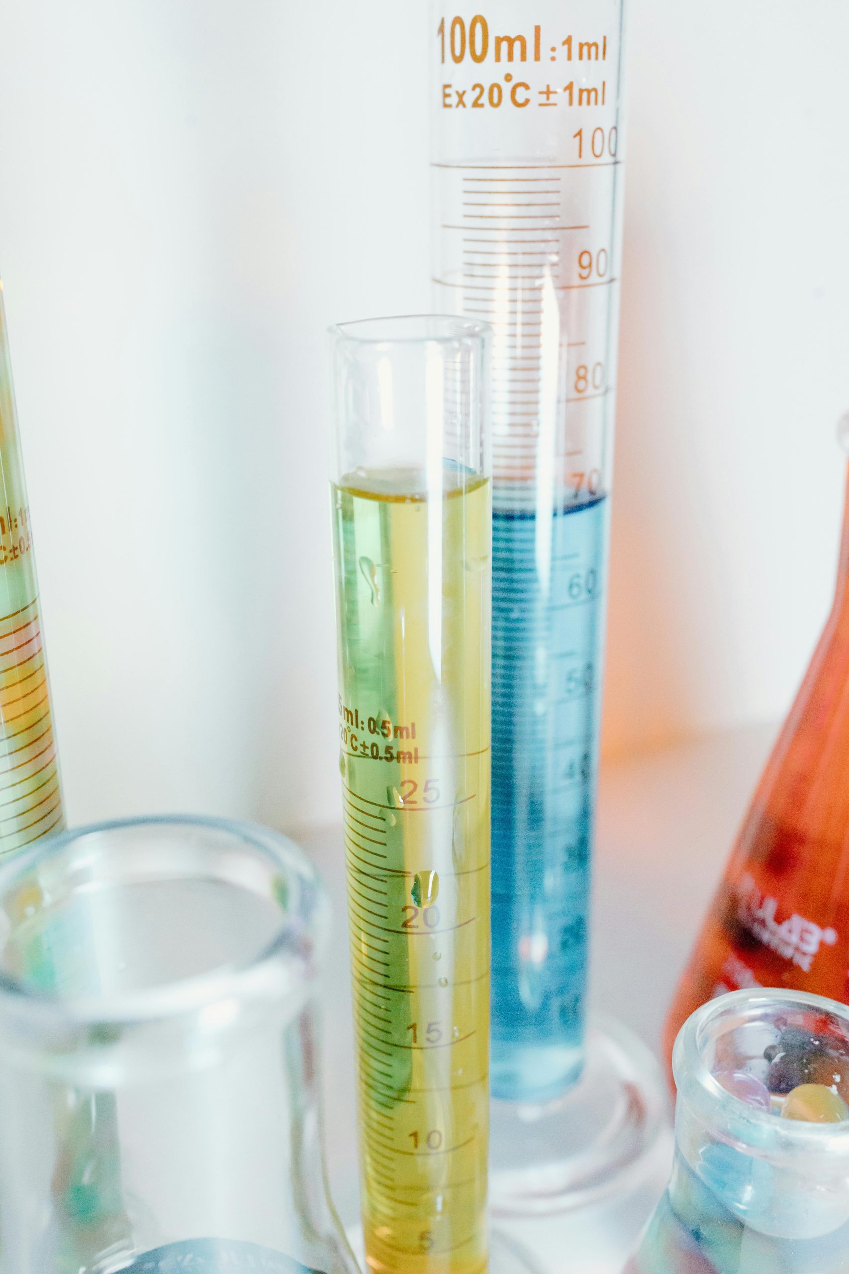 Close-up of colorful liquids in glass laboratory cylinders for scientific experiments. Gros plan de liquides colorés dans des cylindres de laboratoire en verre pour des expériences scientifiques.