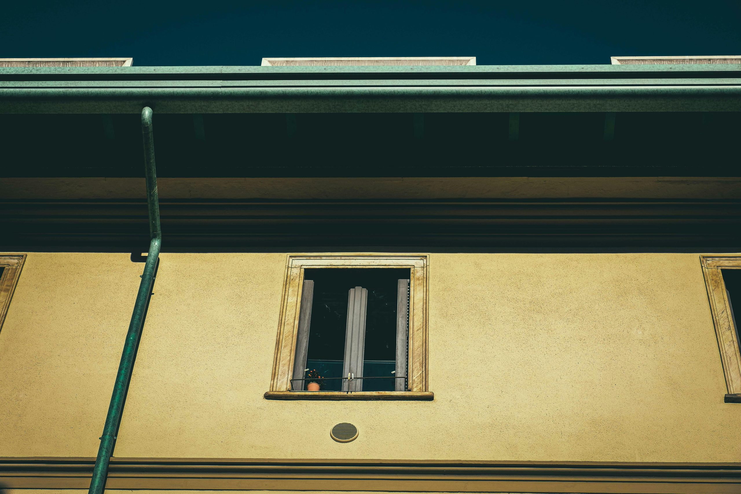From below of aged dwelling building exterior with window on front wall in city in sunlight Vue de bas d'une façade de bâtiment d'habitation ancien avec fenêtre sur le mur frontal en ville sous le soleil