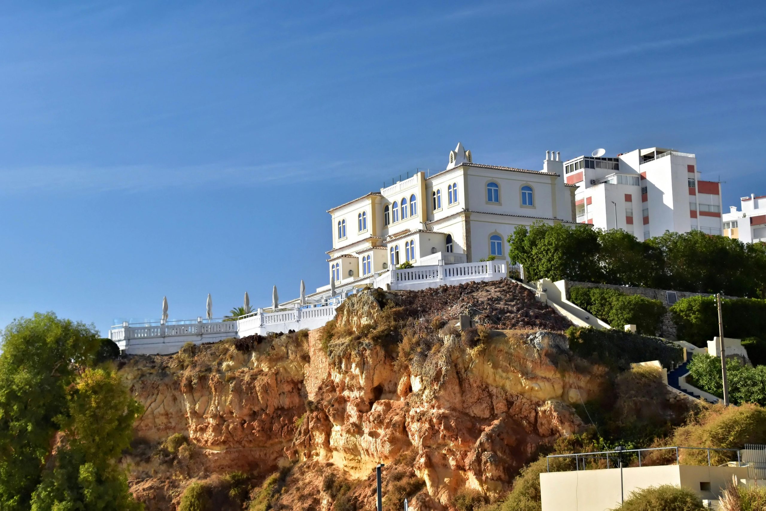 Élégante villa sur une falaise rocheuse de l'Algarve avec un ciel bleu clair dans le district de Faro, au Portugal.