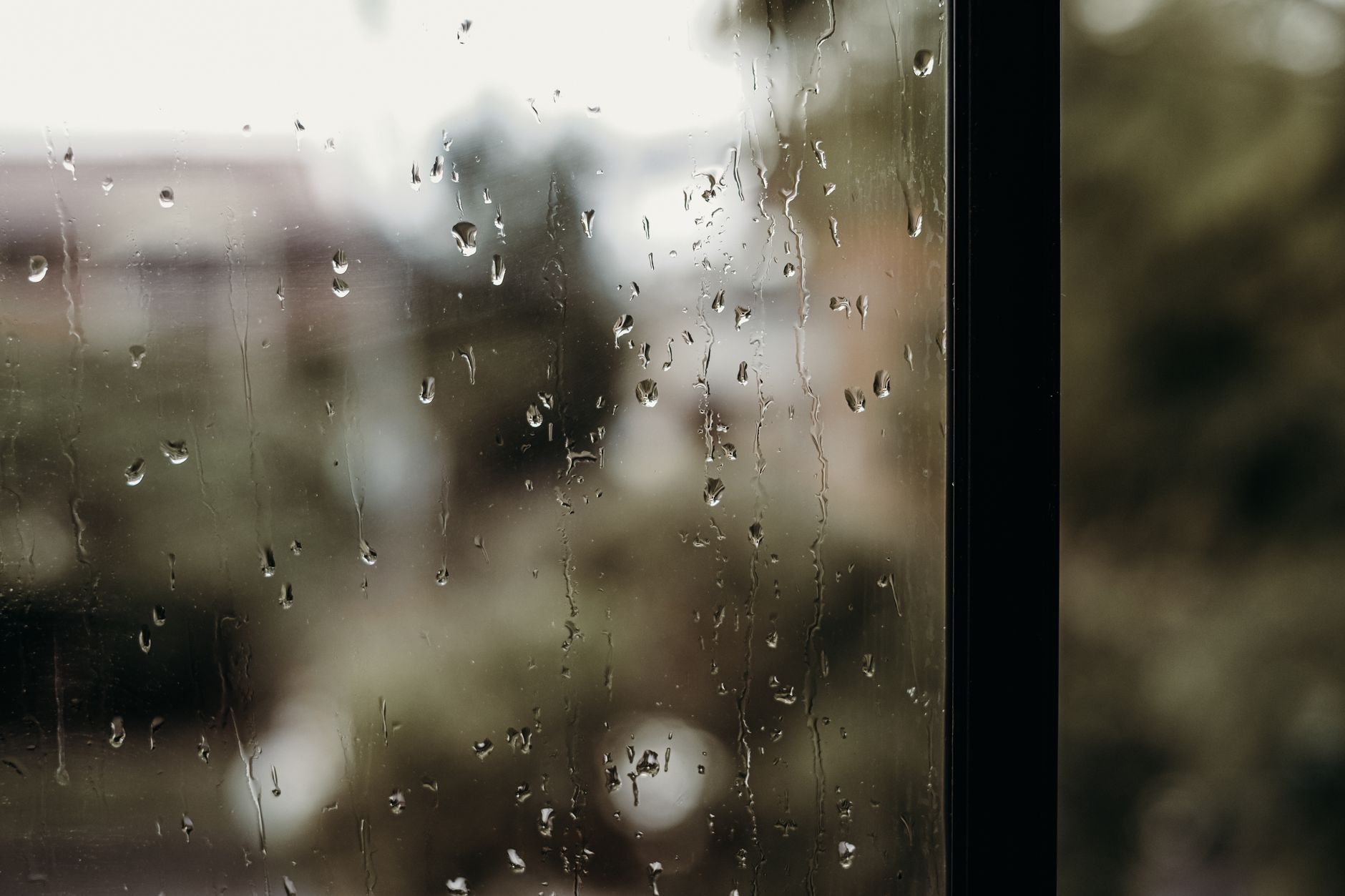Gouttes de pluie ruisselant sur une vitre de maison