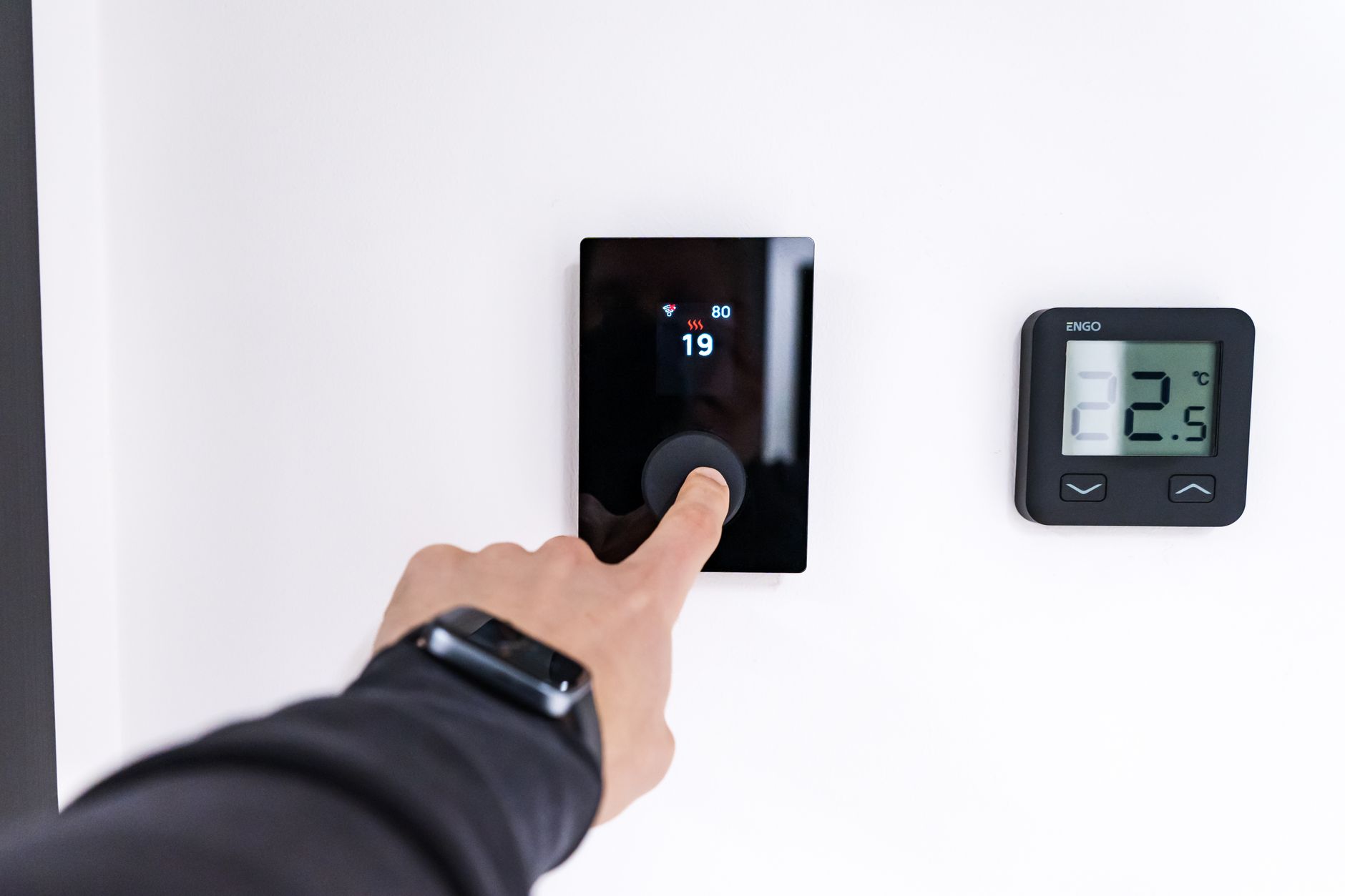 Main réglant un thermostat numérique