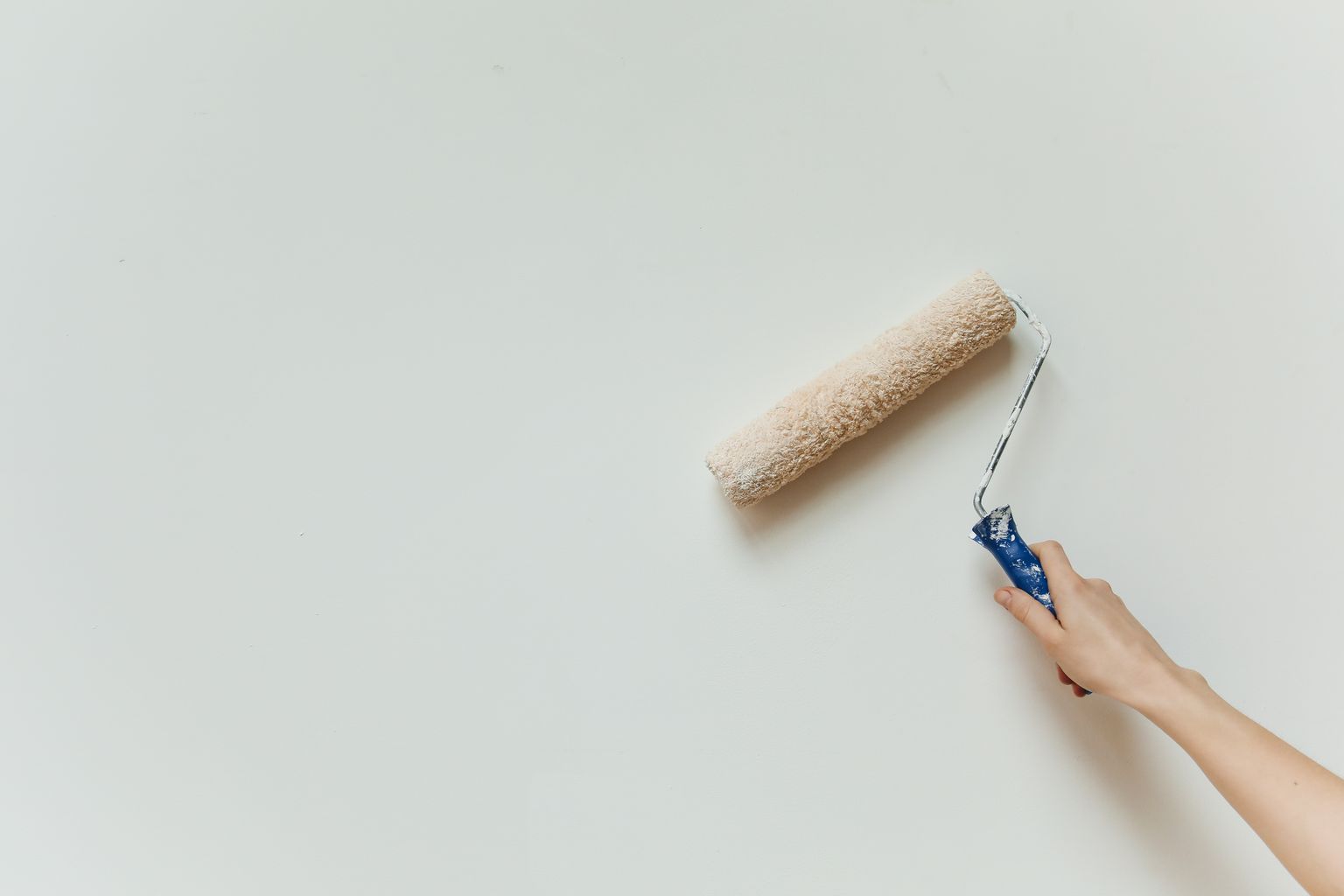 Main appliquant une couche de peinture