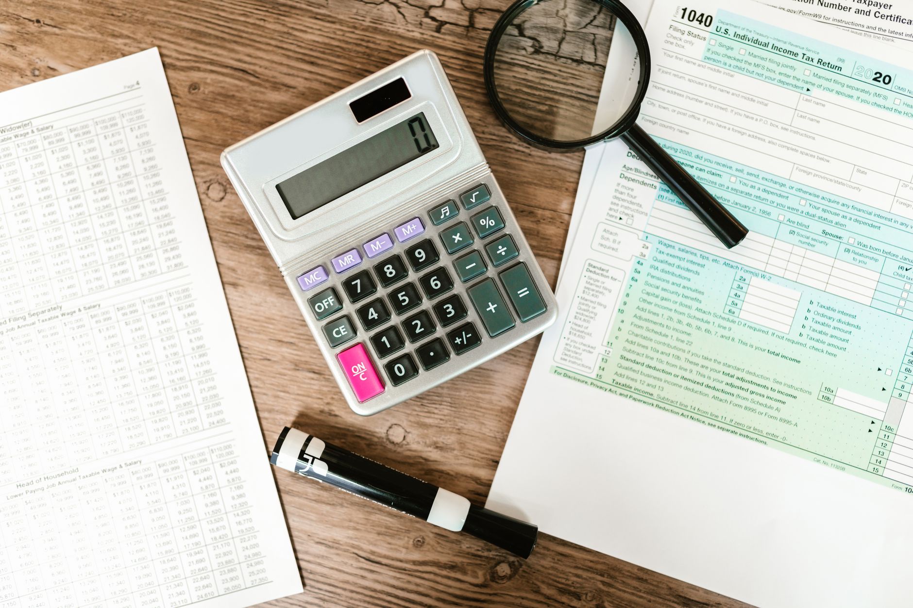 Formulaires d'impôt, calculatrice et loupe sur un bureau