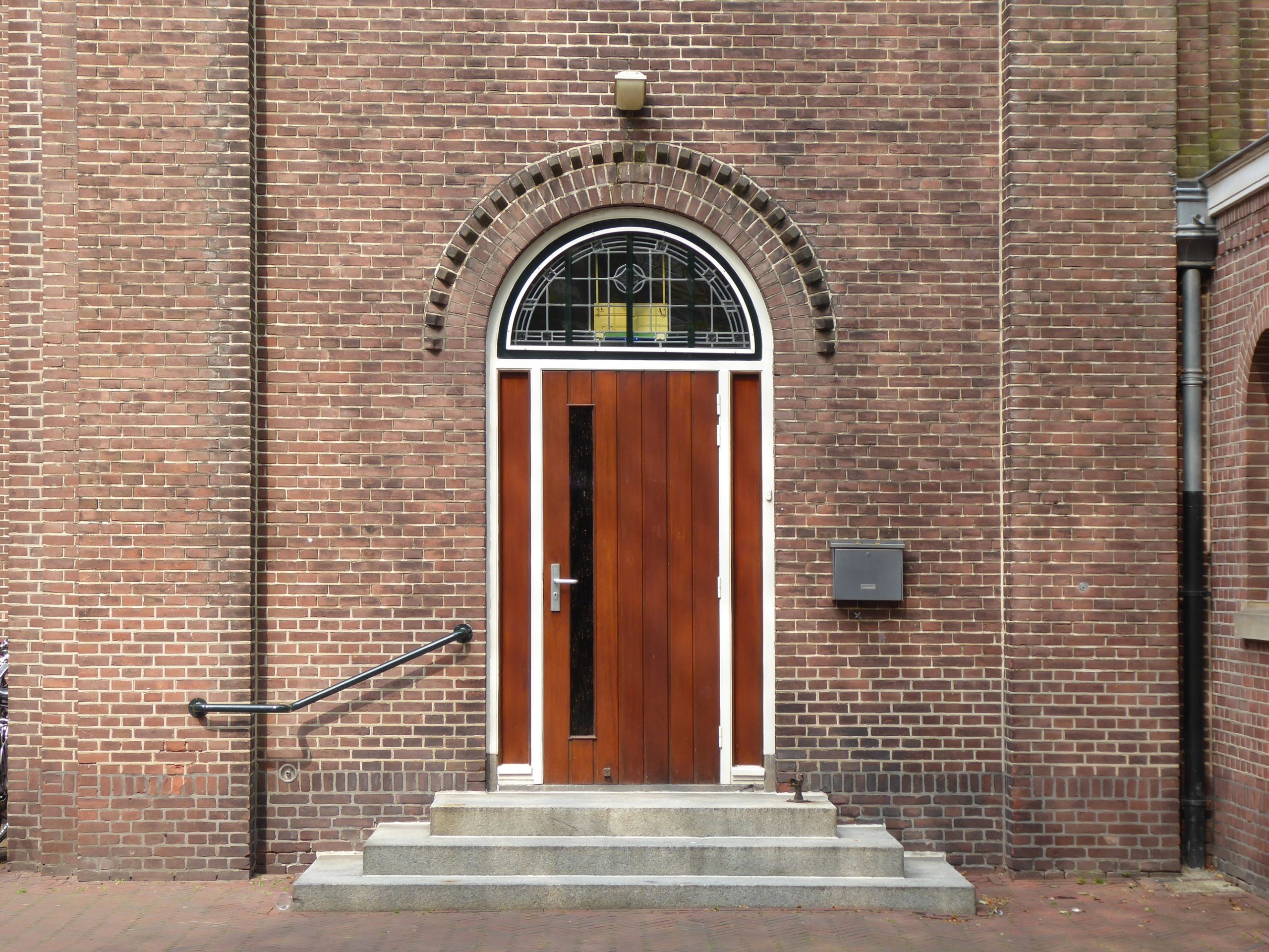 Porte d'entrée en bois sous une arche en briques