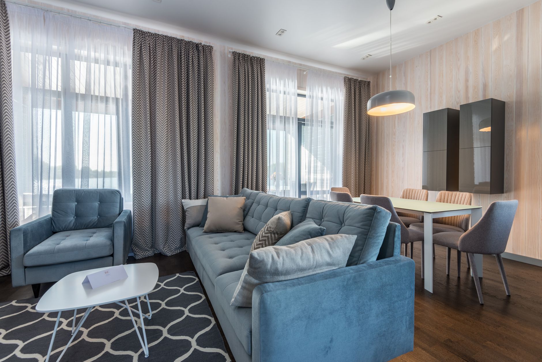 Canapé bleu et fauteuils dans un logement meublé